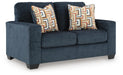 Alyesmore Loveseat by Ashley Furniture, angled view showing plush beige fabric and cushioned armrests for cozy seating.