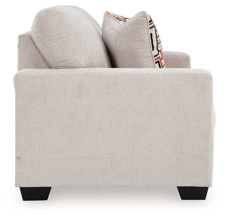 A Ashley Furniture Aviemore loveseat with plush beige upholstery and wooden legs, shown from a side angle.