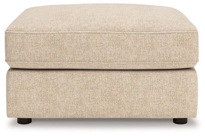 Ashley Furniture Seyler oversized accent ottoman with plush fabric and sturdy wooden legs, shown from a head-on angle.