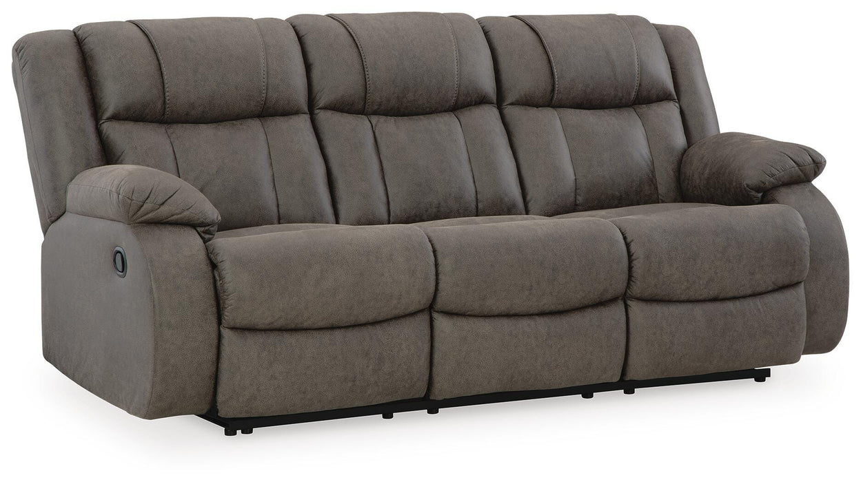 Ashley Furniture First Base reclining sofa shown from an angled view, featuring plush cushions and a reclining mechanism.