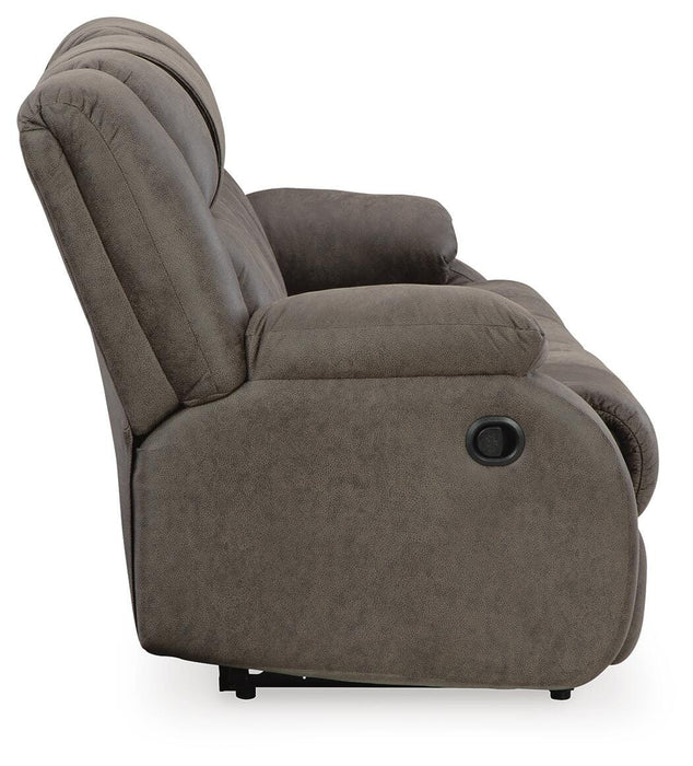 Ashley Furniture First Base reclining sofa with plush cushions and a neutral fabric, shown from the side in a modern living room setting.