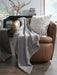 Ashley Furniture Anawood throw blanket featuring a cozy, textured design in warm earthy tones, perfect for adding style and comfort.