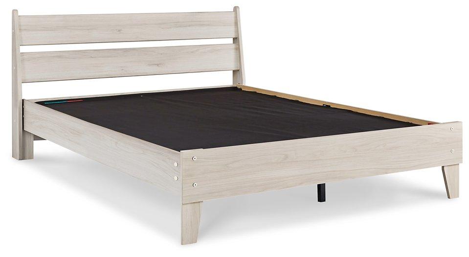 Ashley Furniture Socalle Panel Bed with a wooden frame and headboard, showcasing a modern design in a well-lit bedroom setting.