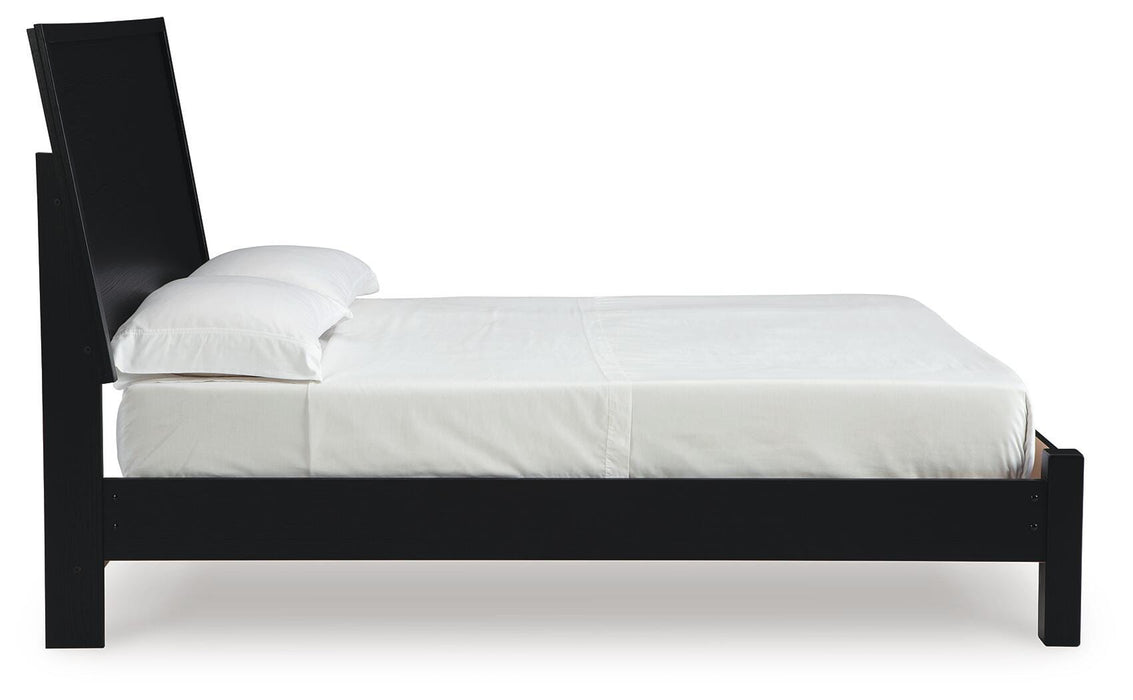 Ashley Furniture Danziar Bed with beige upholstered headboard and wooden frame, shown from a side angle.