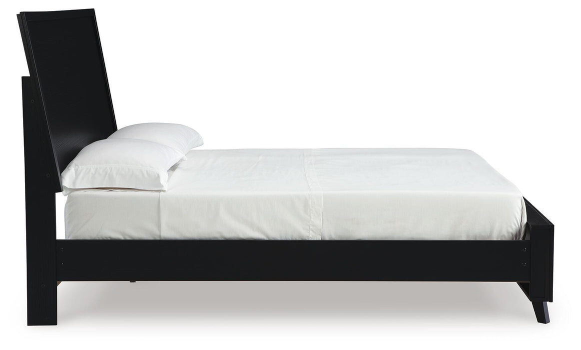 Ashley Furniture Danziar Bed with a wooden frame and upholstered headboard, shown from a side view in a modern bedroom setting.