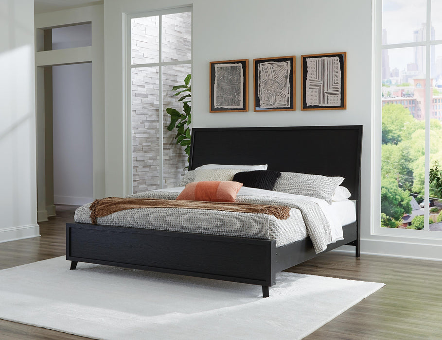 Ashley Furniture Danziar Bed with a wooden frame and neutral upholstered headboard, shown in a modern bedroom setting.