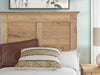 Ashley Furniture Makidern Bed with a wooden frame and detailed headboard, shown in a bedroom setting.