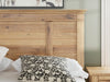 Ashley Furniture Makidern bed with a wooden frame, detailed headboard, and neutral upholstery, shown in a close-up view.