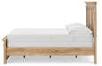 Ashley Furniture Makidern Bed with a wooden frame and upholstered headboard, shown from a side angle in a modern bedroom setting.