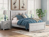 Ashley Furniture Makidern Bed showing a modern wooden bed frame with a neutral finish and clean lines in a bedroom setting.