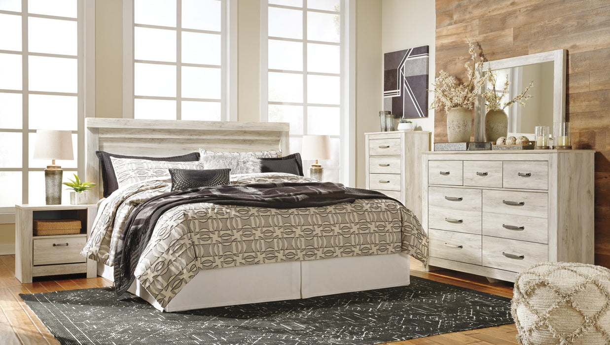 Ashley Furniture Bellaby Bed with a wooden headboard and frame, showcasing a modern bedroom centerpiece.