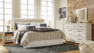 Ashley Furniture Bellaby Bed with a wooden headboard and frame, showcasing a modern bedroom centerpiece.