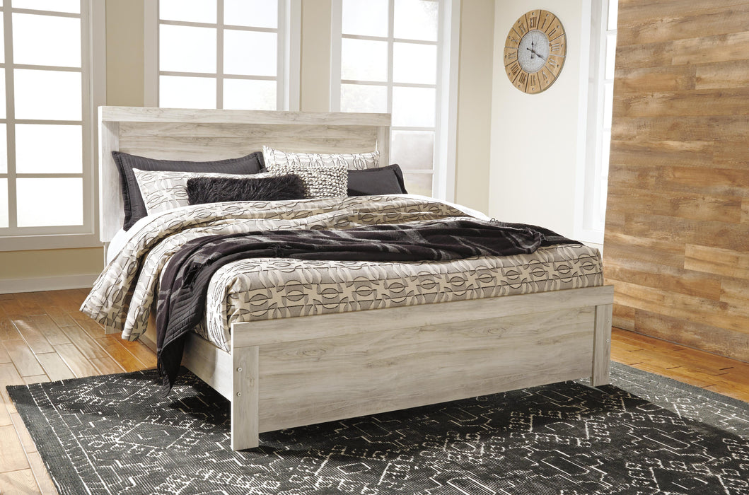 Ashley Furniture Bellaby Bed with a wooden frame and stylish headboard, shown in a cozy bedroom setting.