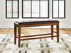 Ashley Furniture Ralene counter height dining bench with wooden legs and cushioned seat for kitchen or dining room use.