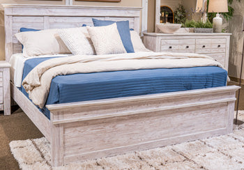 Ashley Furniture Makidern Bed with a stylish wooden frame and neutral fabric headboard, shown in a modern bedroom setting.